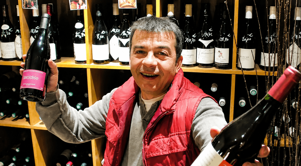 Paco Mora dans la Cave d'Ivry à Ivry-sur-Seine présentant des bouteilles de vins sélectionnées dans son caviste indépendant.